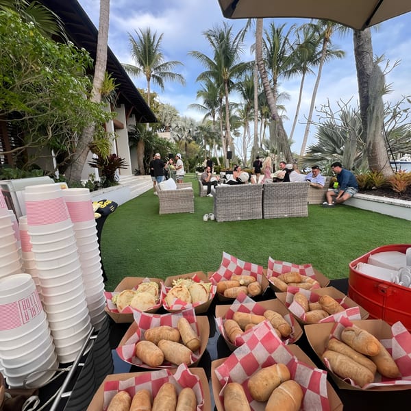 La Latina's outdoor event with Venezuelan food, including arepas and tequeños, and guests relaxing on a grassy patio.